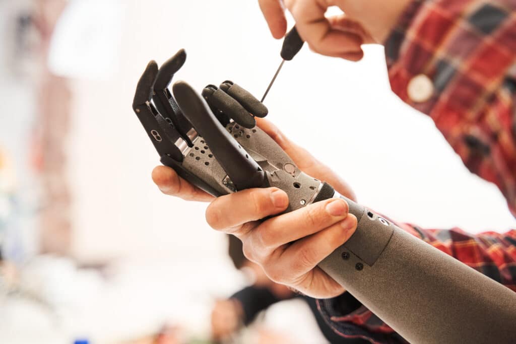 Man scientist twisting with screwdriver contacts in mechanical plastic hand