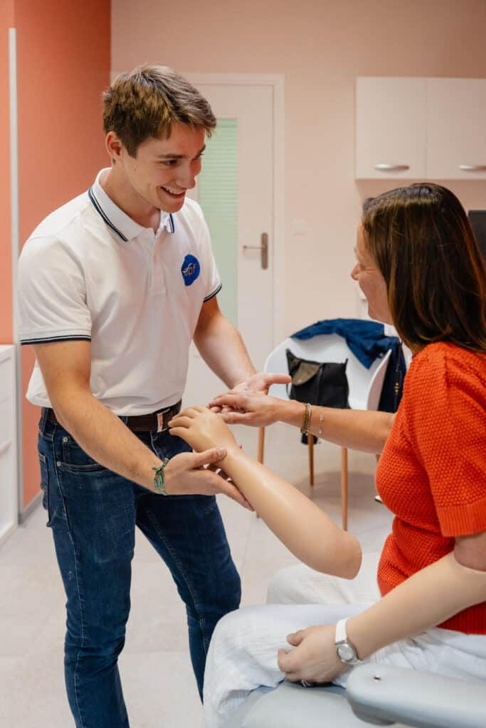 Technicien epf en polo blanc montre un avant-bras prothétique à une femme souriante. Interaction professionnelle autour de la prothèse.